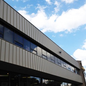 Commercial building renovation and modernization project curing water penetration problems on a stucco office building by installing a new Standing-Seam Facade and trim